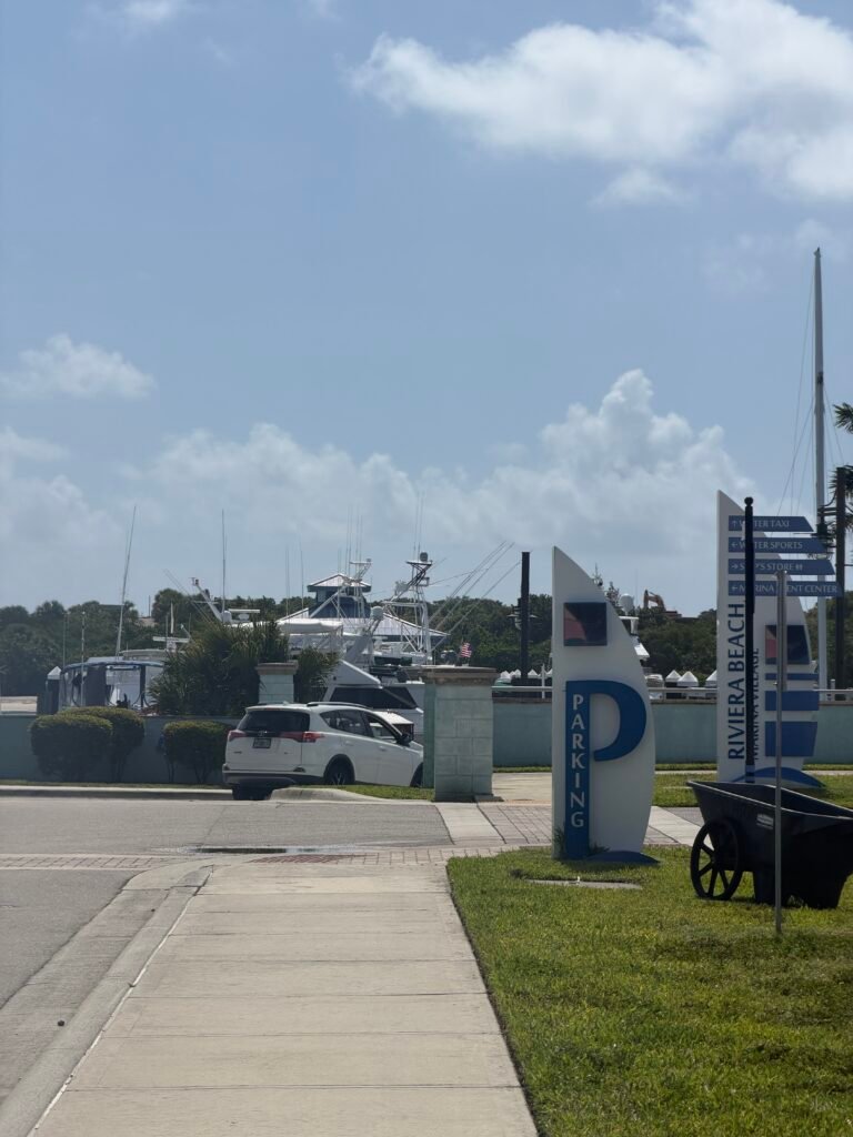 Entrance to Riviera Beach Marina Village, with a parking sign and directional signs pointing to the water taxi